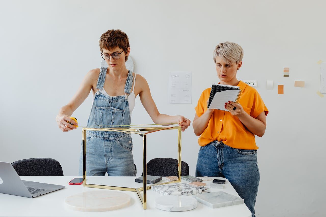 Two women construct a part of a furniture package